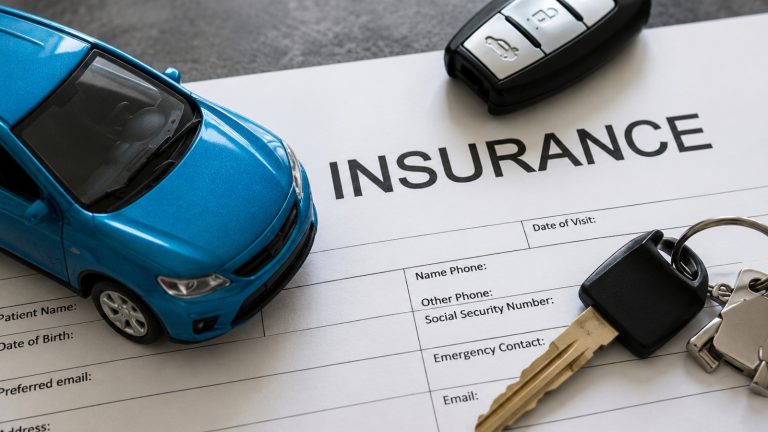 blue toy car and car keys rest on top of an insurance document