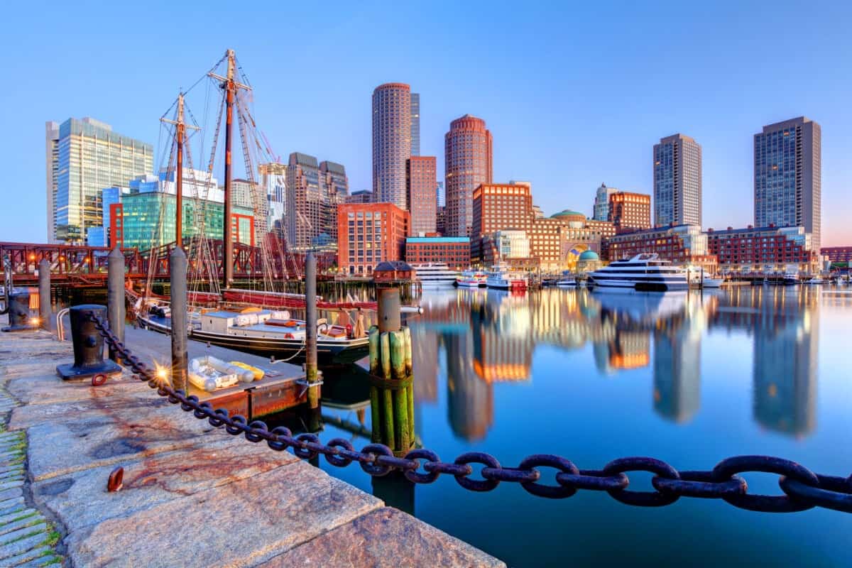 Boston skyline and harbor reflecting on water with a chain