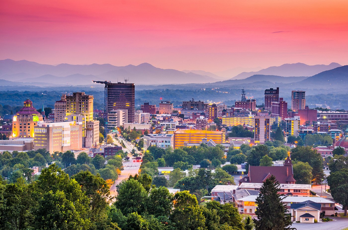 Sunset skyline of a city nestled beneath distant mountain ranges