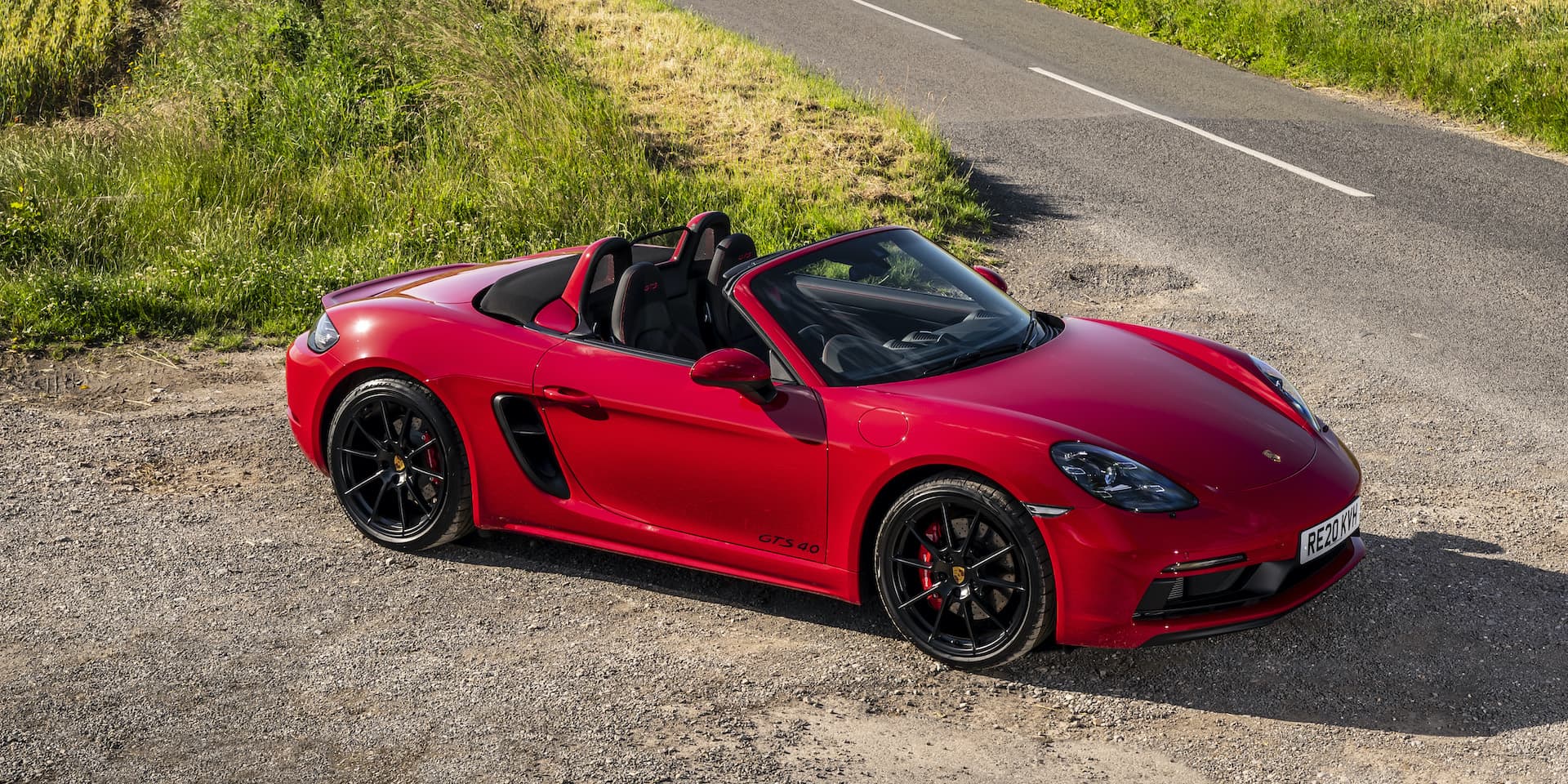 A red Porsche 718 Boxter standing on the side of a highway