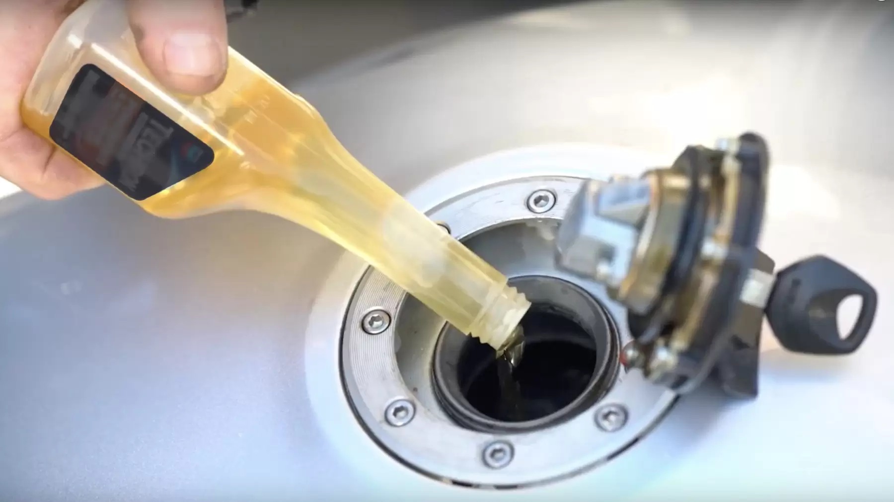 Pouring a yellow liquid fuel additive into the fuel tank