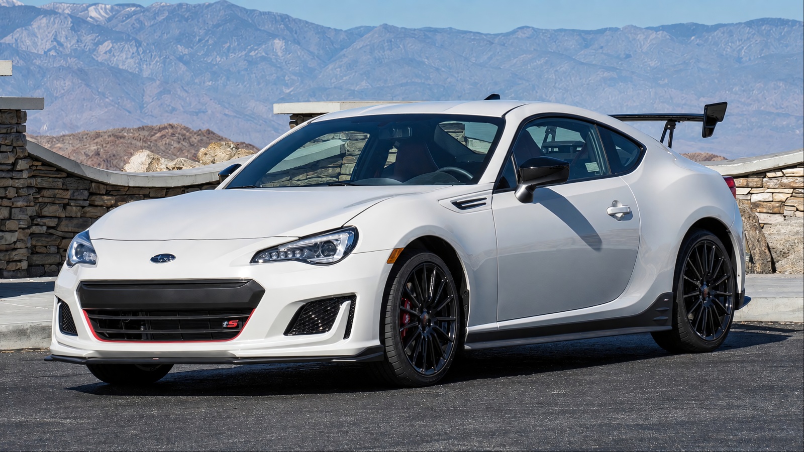 Subaru BRZ parked against a scenic mountain backdrop in bright daylight
