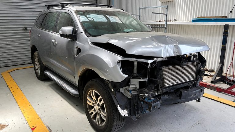 Damaged SUV with front-end collision damage inside a professional body shop