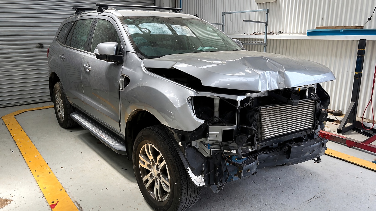 Damaged SUV with front-end collision damage inside a professional body shop