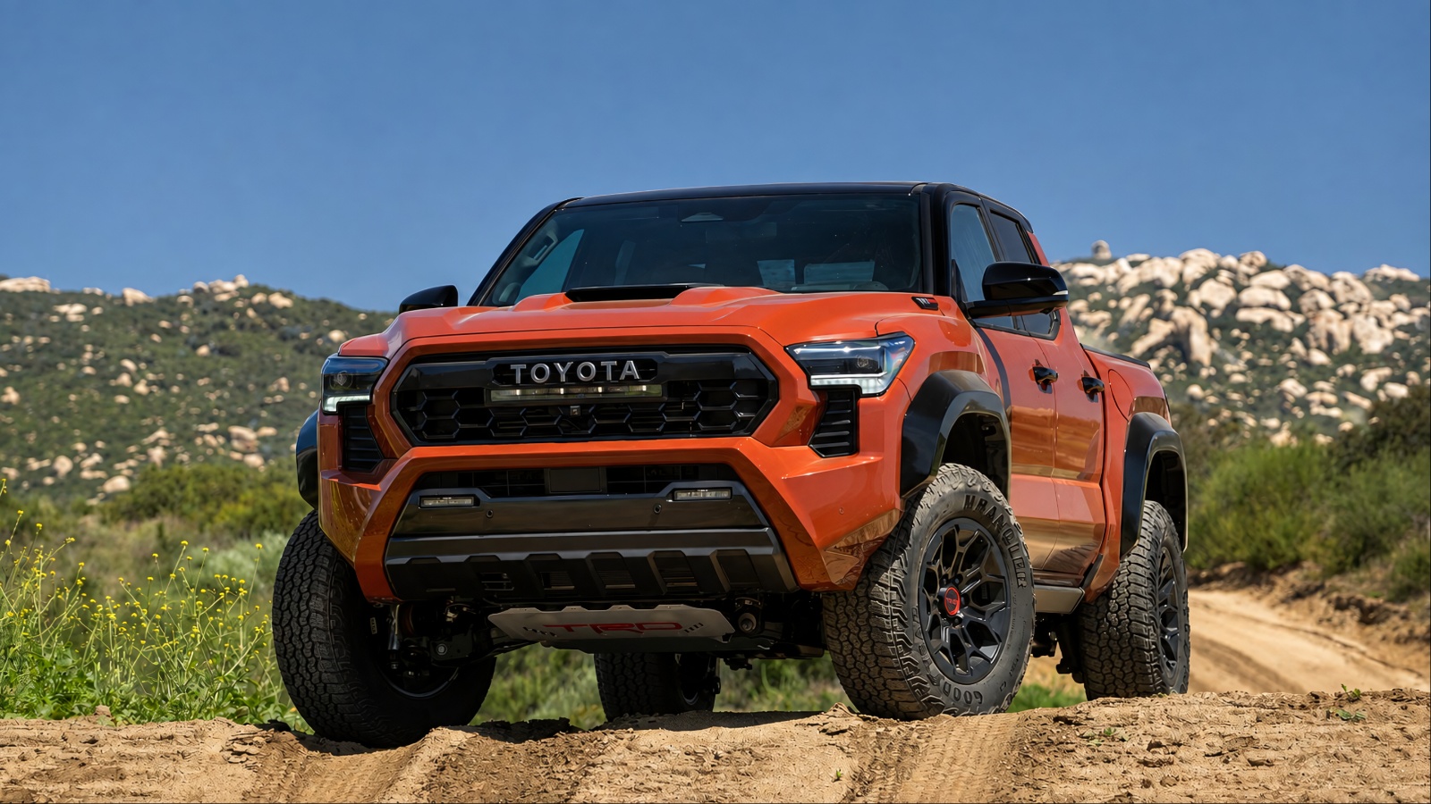 Toyota Tacoma is standing on a road filled with desert sand