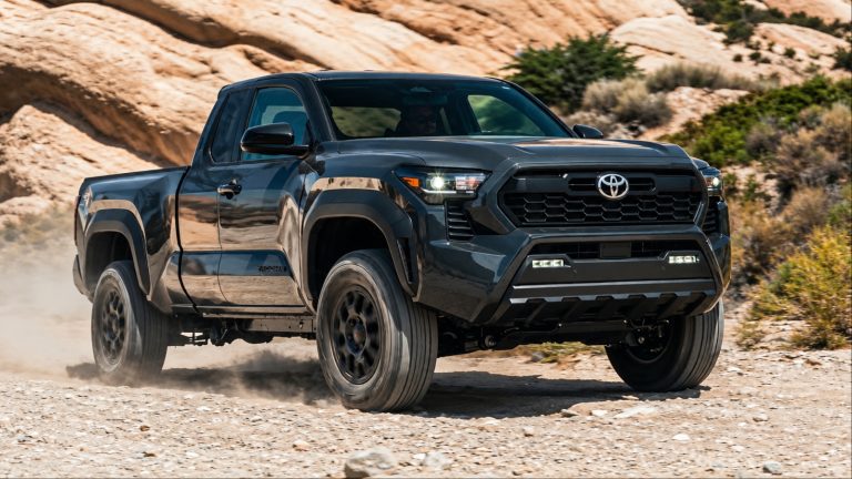 Dark gray Toyota Tacoma pickup truck driving on dirt terrain
