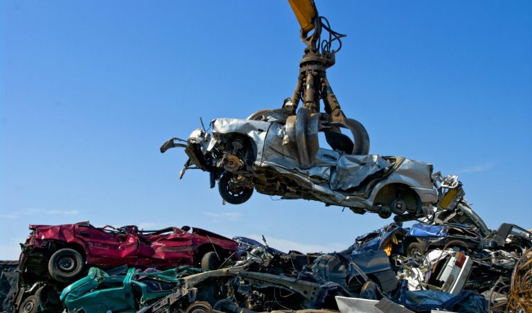 A scrapyard is shown where a car is being scrapped