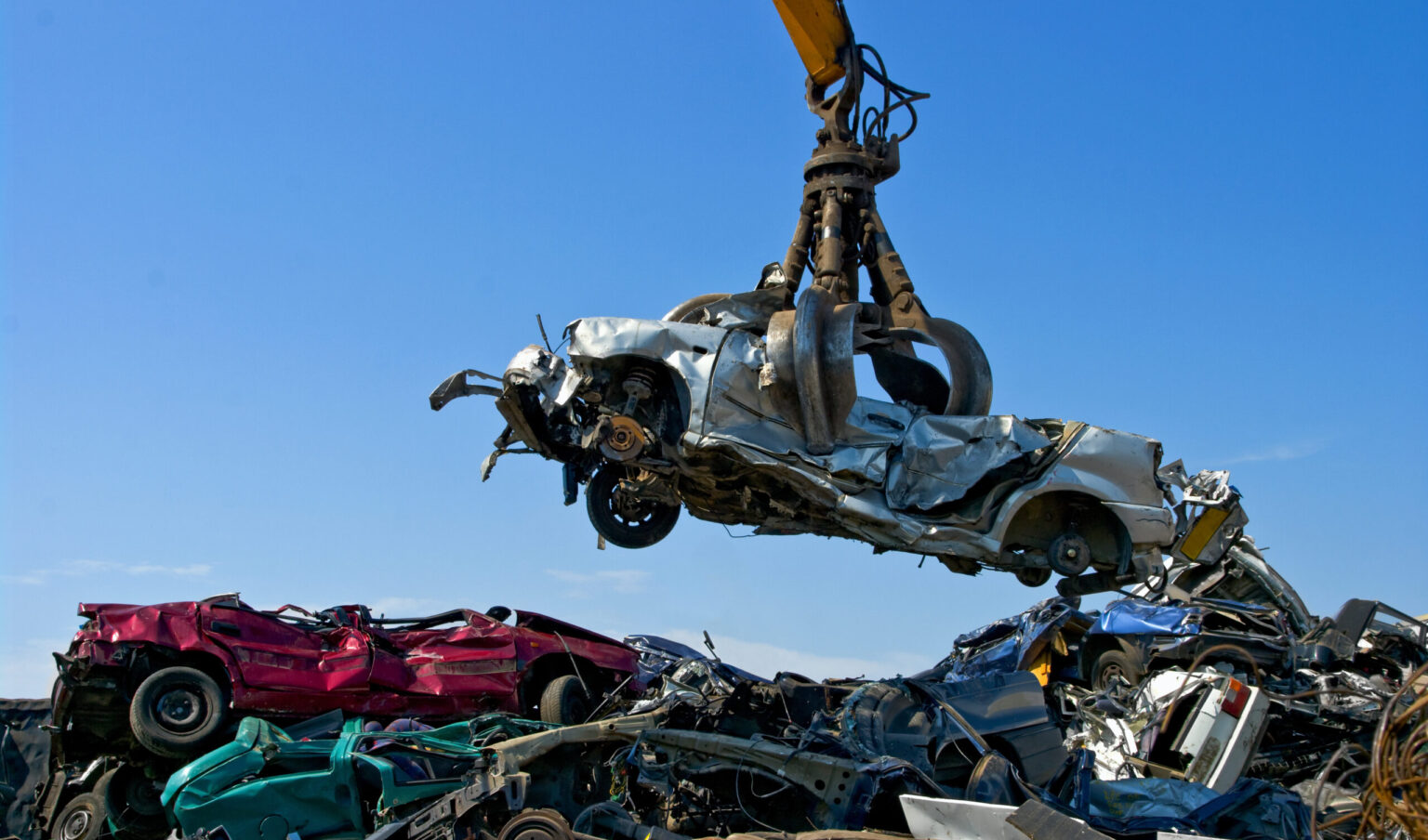 A scrapyard is shown where a car is being scrapped