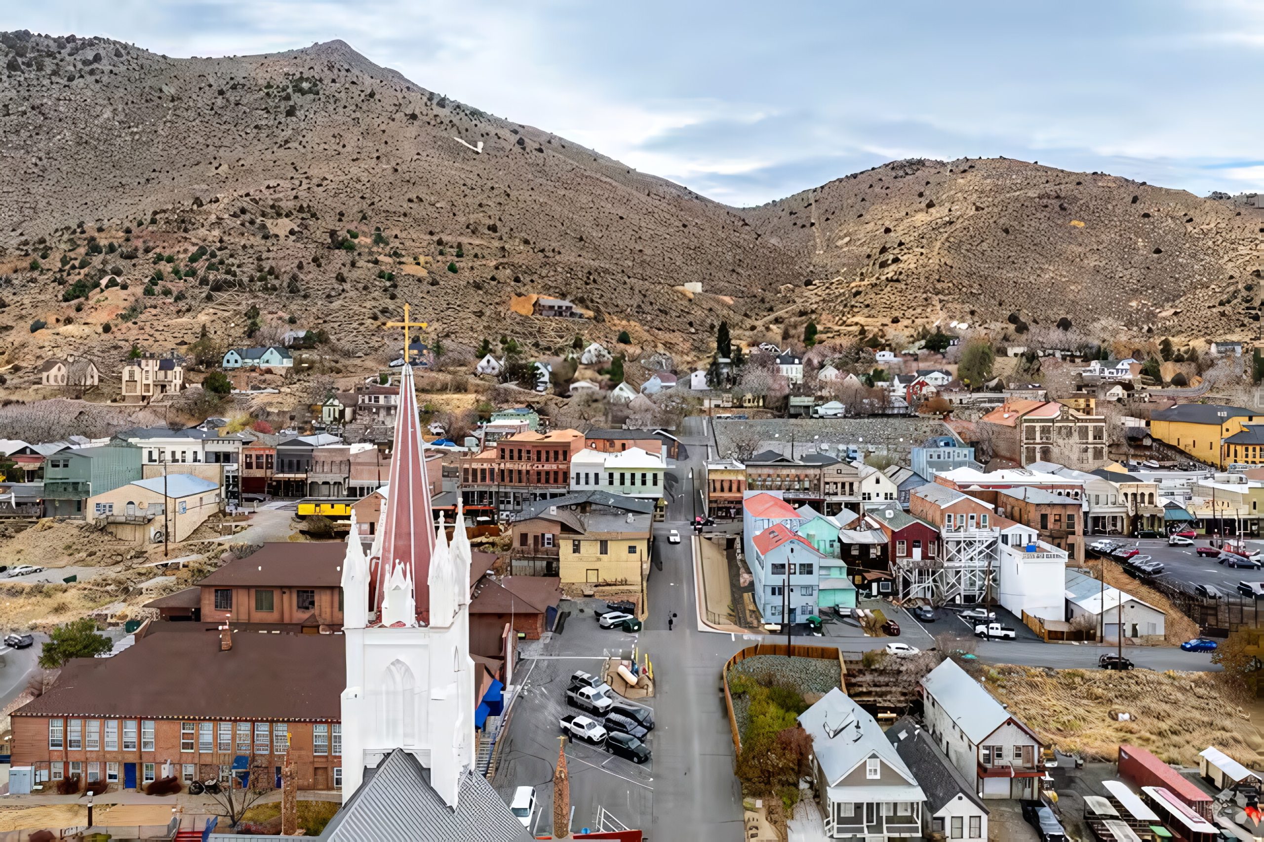 town with a white church steeple beneath barren mountains