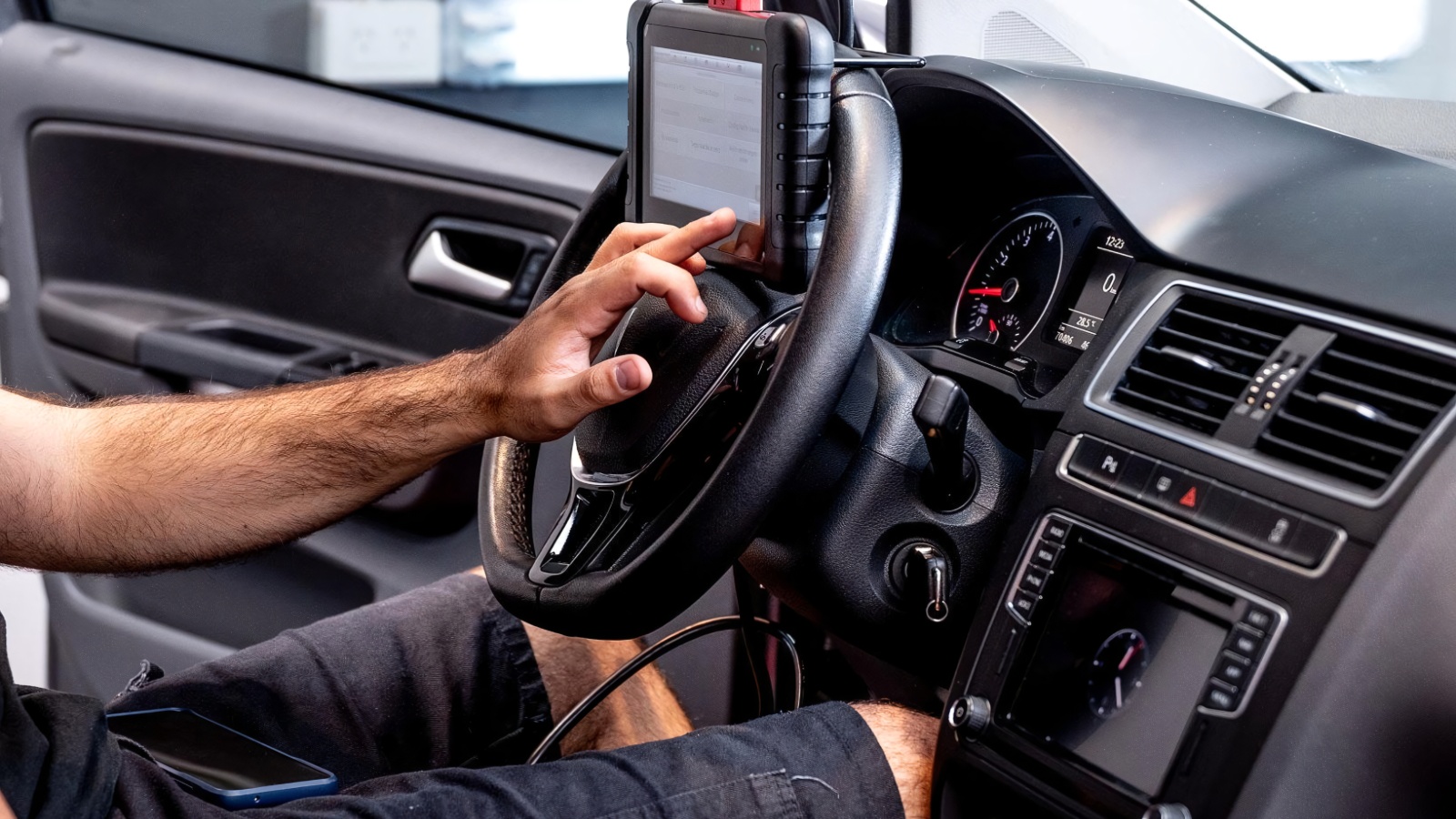 technician uses a diagnostic tablet computer mounted on a car steering wheel