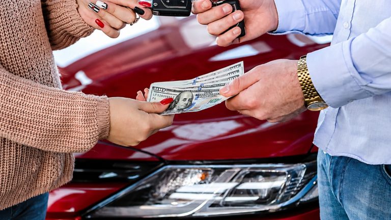 A car buyer handing cash to a dealer during a vehicle purchase