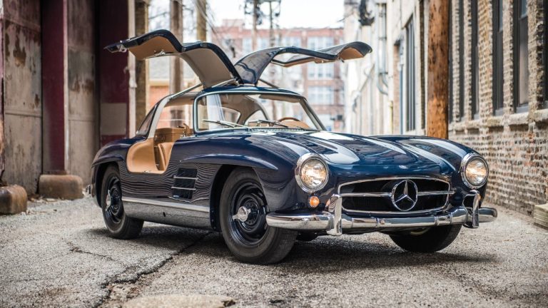 A classic Mercedes-Benz 300SL Gullwing sits in a city alley with its iconic doors raised