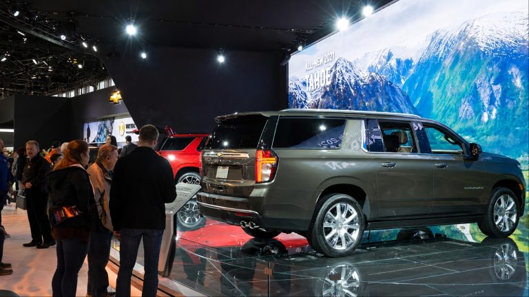 A full-size SUV displayed at an auto show, drawing attention from visitors