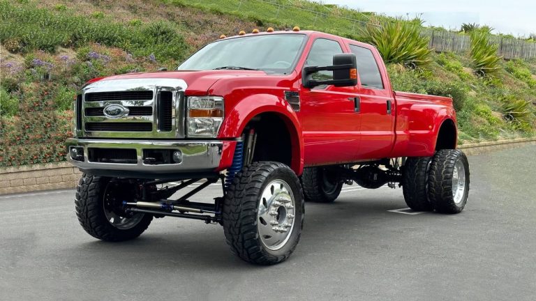 A lifted red Ford Super Duty truck with oversized tires parked outdoors