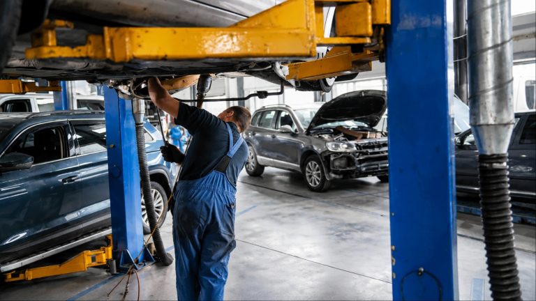 A mechanic performs underbody repairs on a vehicle inside a professional automotive service workshop