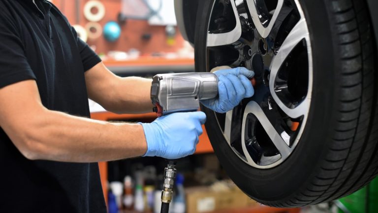 A mechanic uses an impact wrench to service a vehicle’s wheel in an automotive workshop
