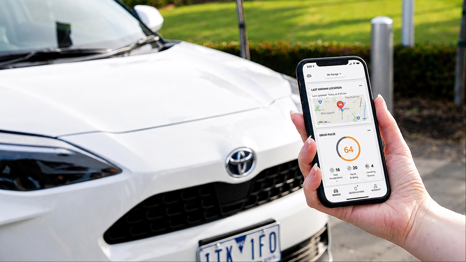 A smartphone showing connected-car data beside a Toyota vehicle