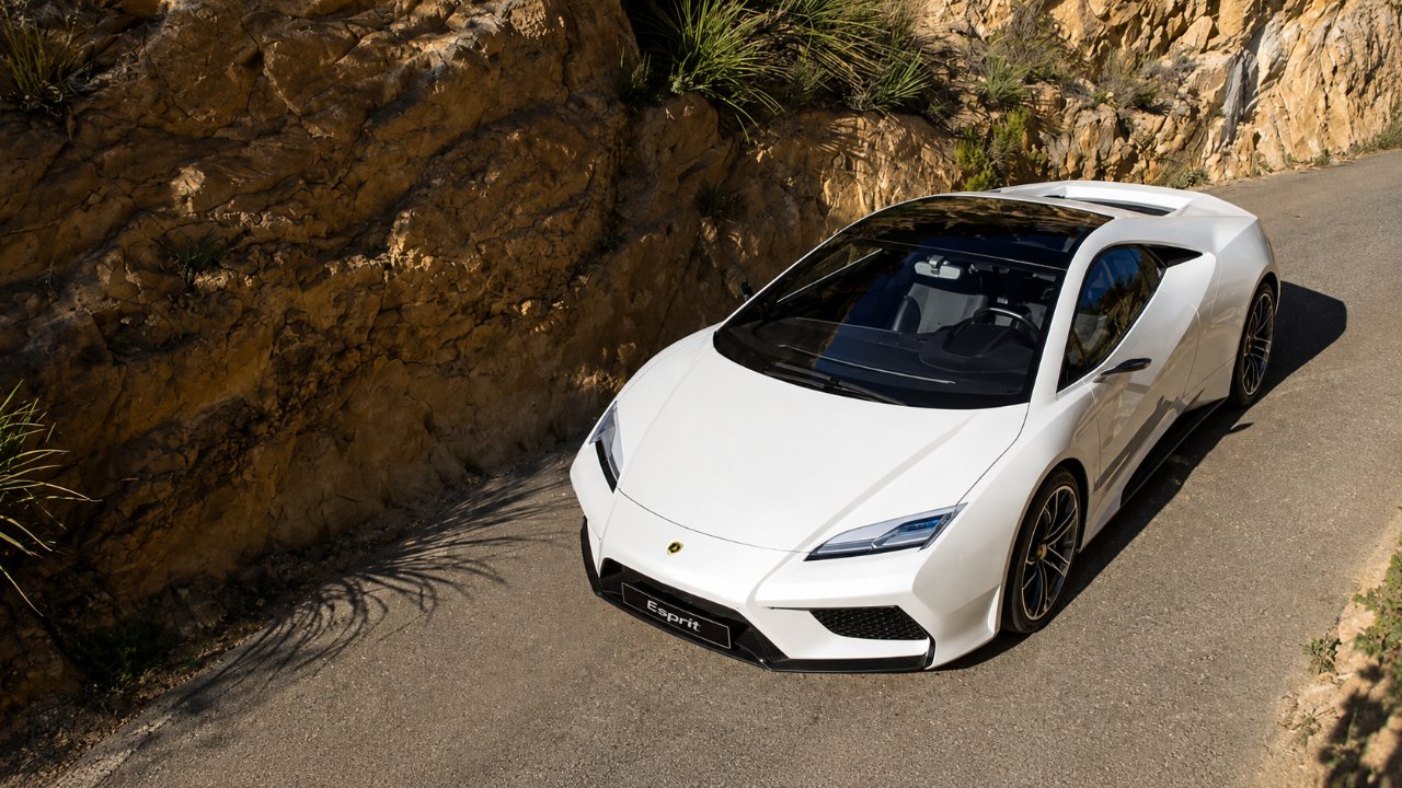 A white Lotus sports car parked on a winding mountain road beside a rocky hillside