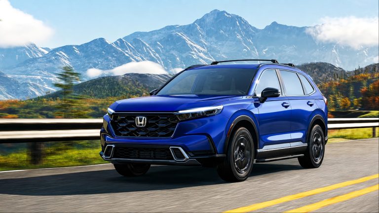 blue Honda SUV drives on a scenic highway with snow-capped mountains in the background