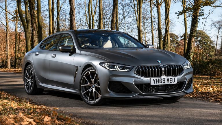 Silver BMW 7-Series parked on a quiet road surrounded by trees