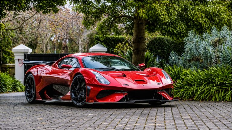 Track-only red hypercar with massive rear wing, parked outside