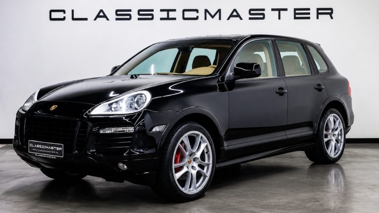 sleek black Porsche SUV parked indoors with bright headlights and custom silver wheels