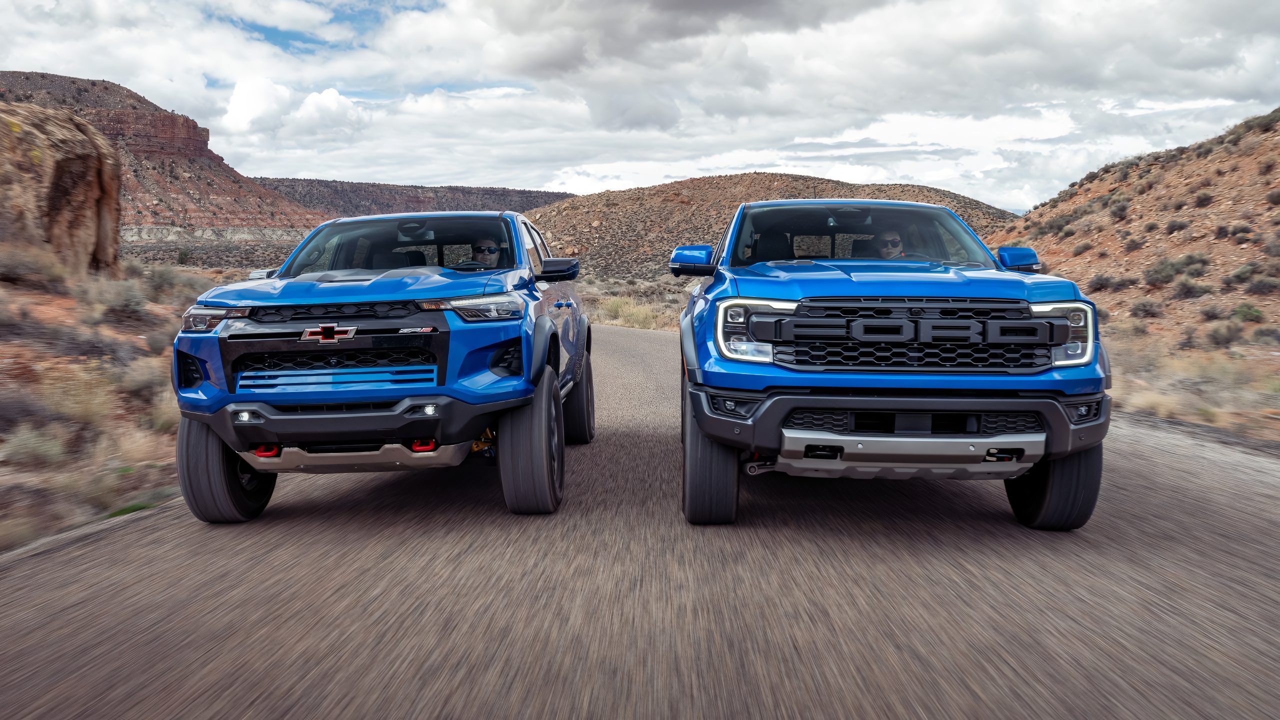 Chevrolet Colorado ZR2 and Ford Ranger Raptor drive side-by-side through rugged desert terrain