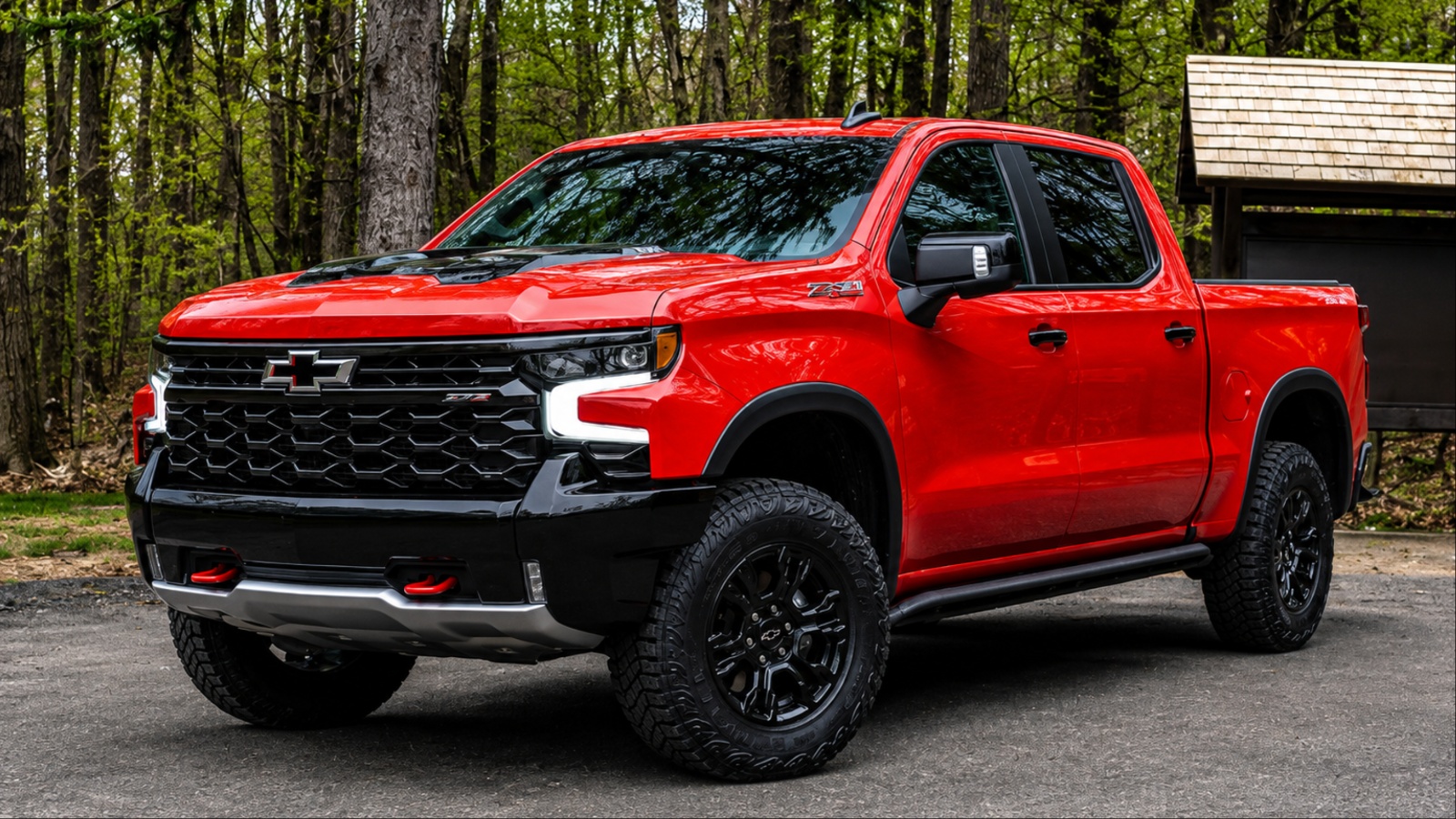 shiny red Silverado is standing in front of forest trees