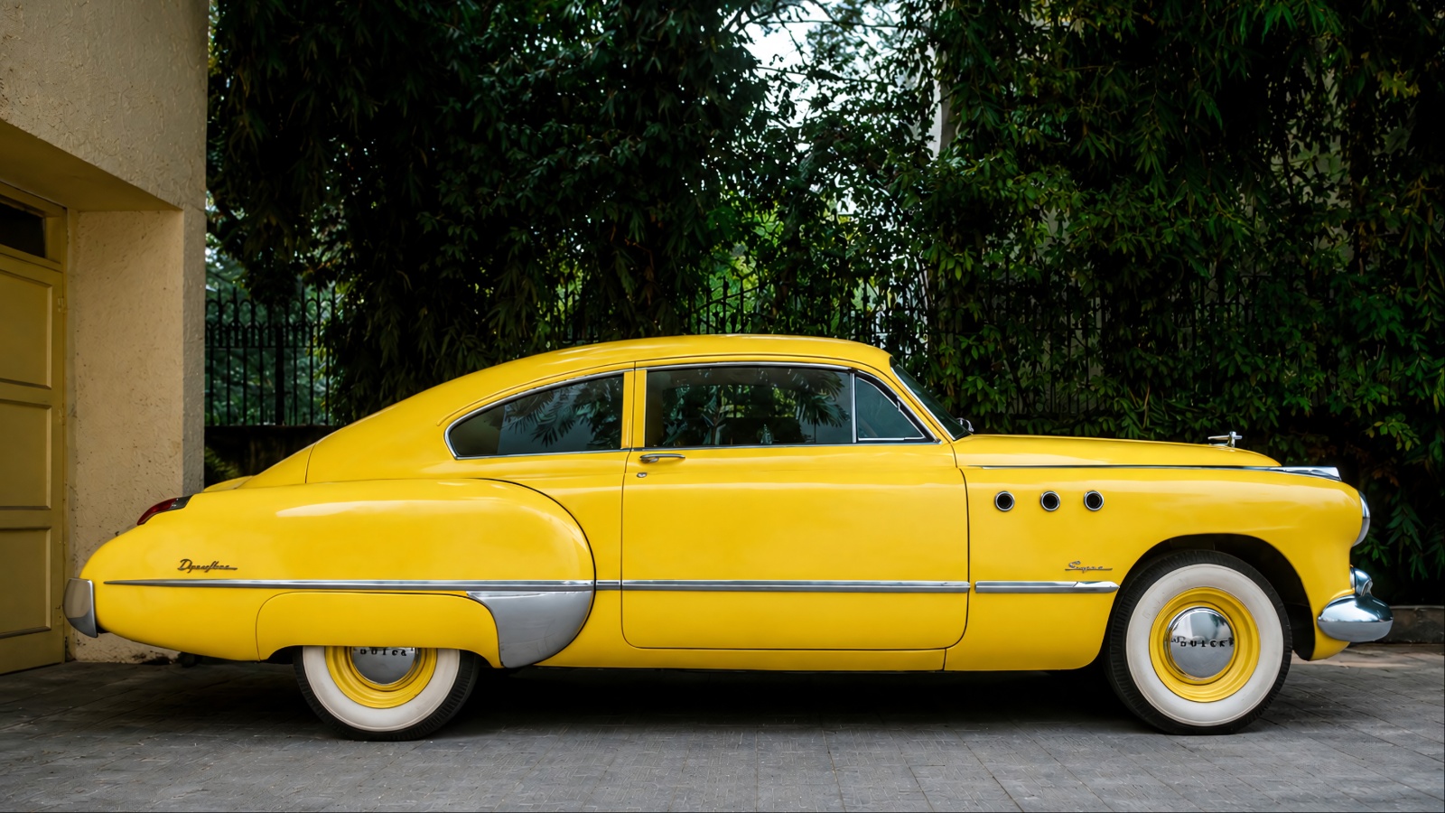A vintage yellow car is standing in an auction showcase