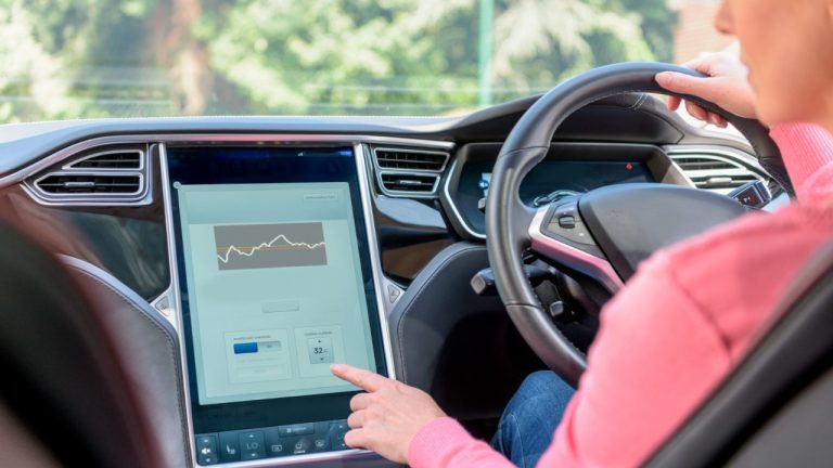 Driver adjusts electric vehicle charging settings through the central touchscreen while driving