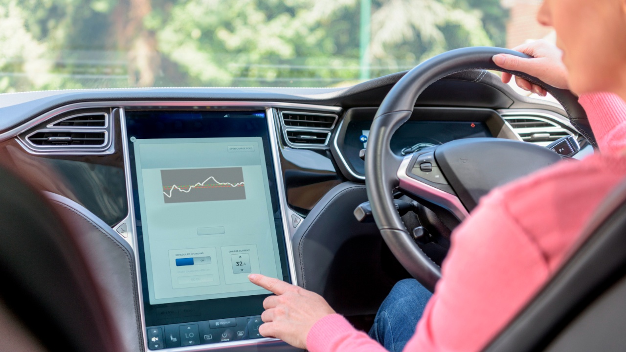 Driver adjusts electric vehicle charging settings through the central touchscreen while driving
