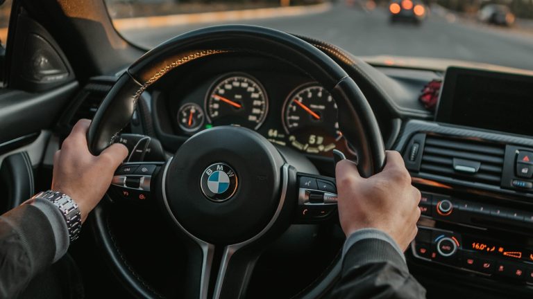 Driver holding a BMW steering wheel while navigating through city traffic