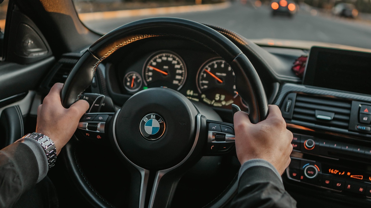 Driver holding a BMW steering wheel while navigating through city traffic