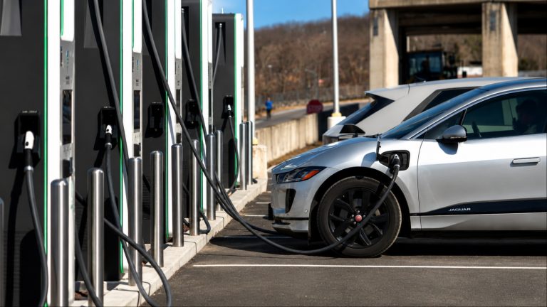 Electric SUV charging at a fast-charging station with multiple charging stalls