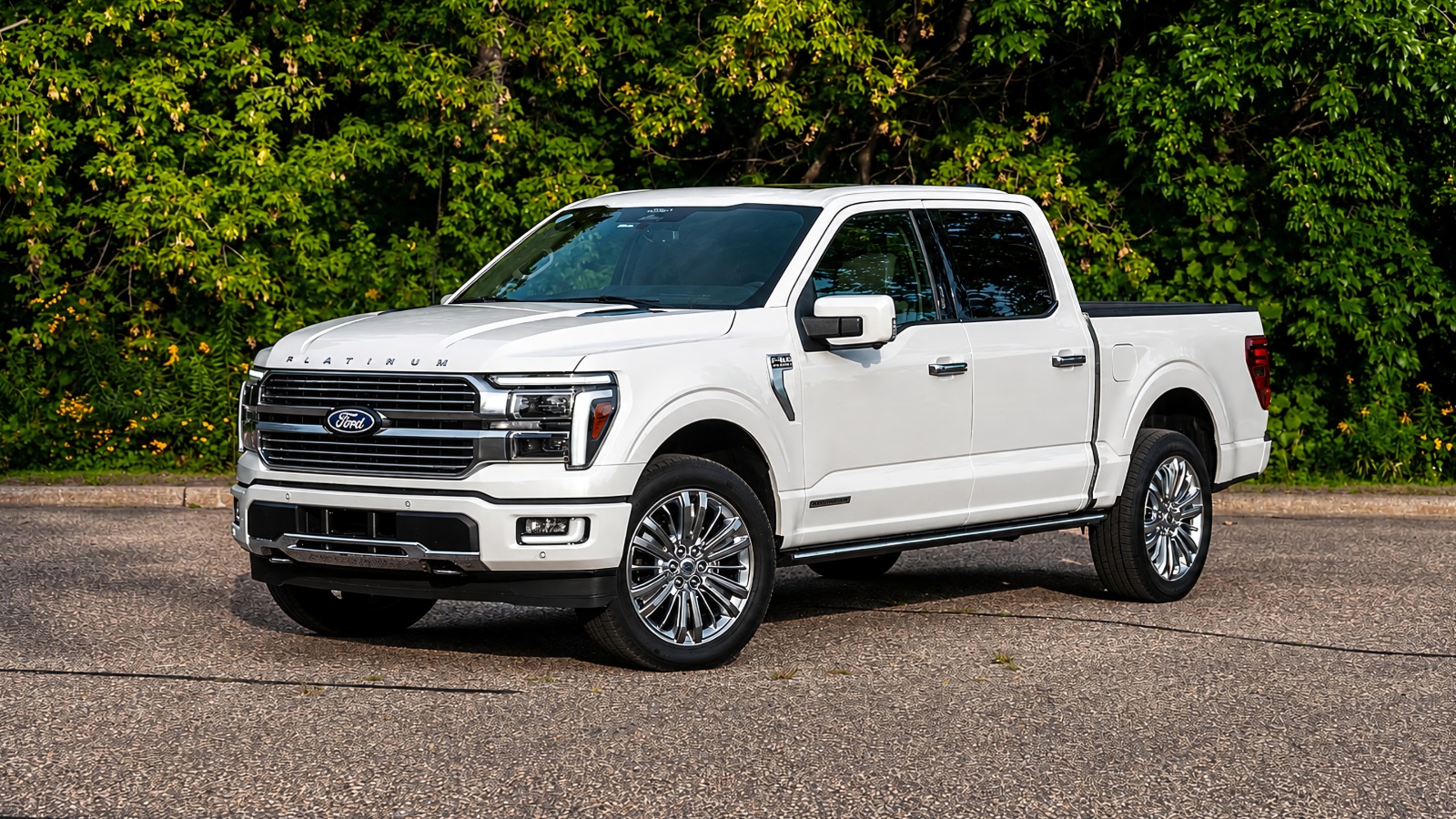 A white Ford F 150 Hybrid is standing in front of small plants