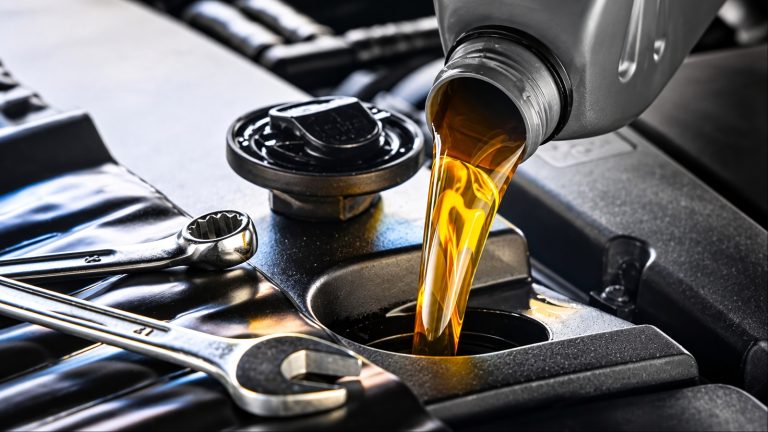 Fresh motor oil pours into an engine beside essential automotive tools