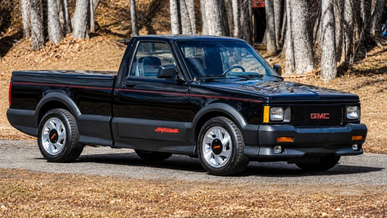 A GMC Syclone is standing in front of woods