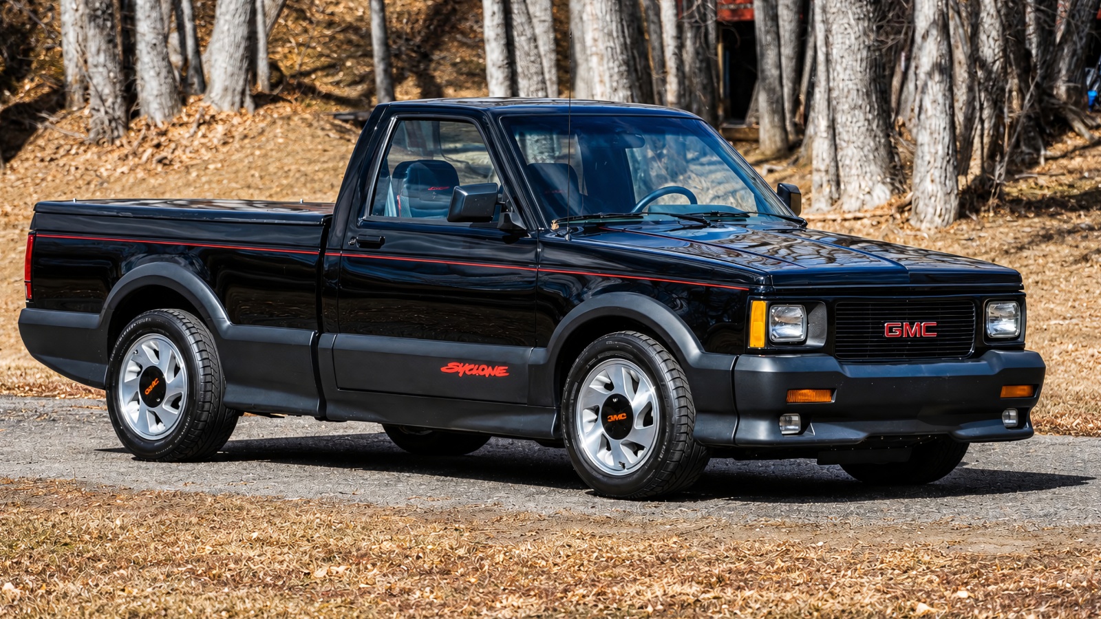 A GMC Syclone is standing in front of woods