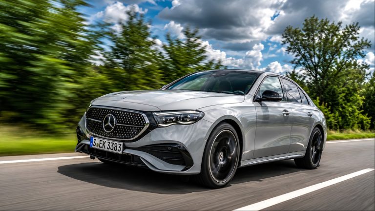 Gray Mercedes-Benz E-Class driving on a highway with motion-blurred trees