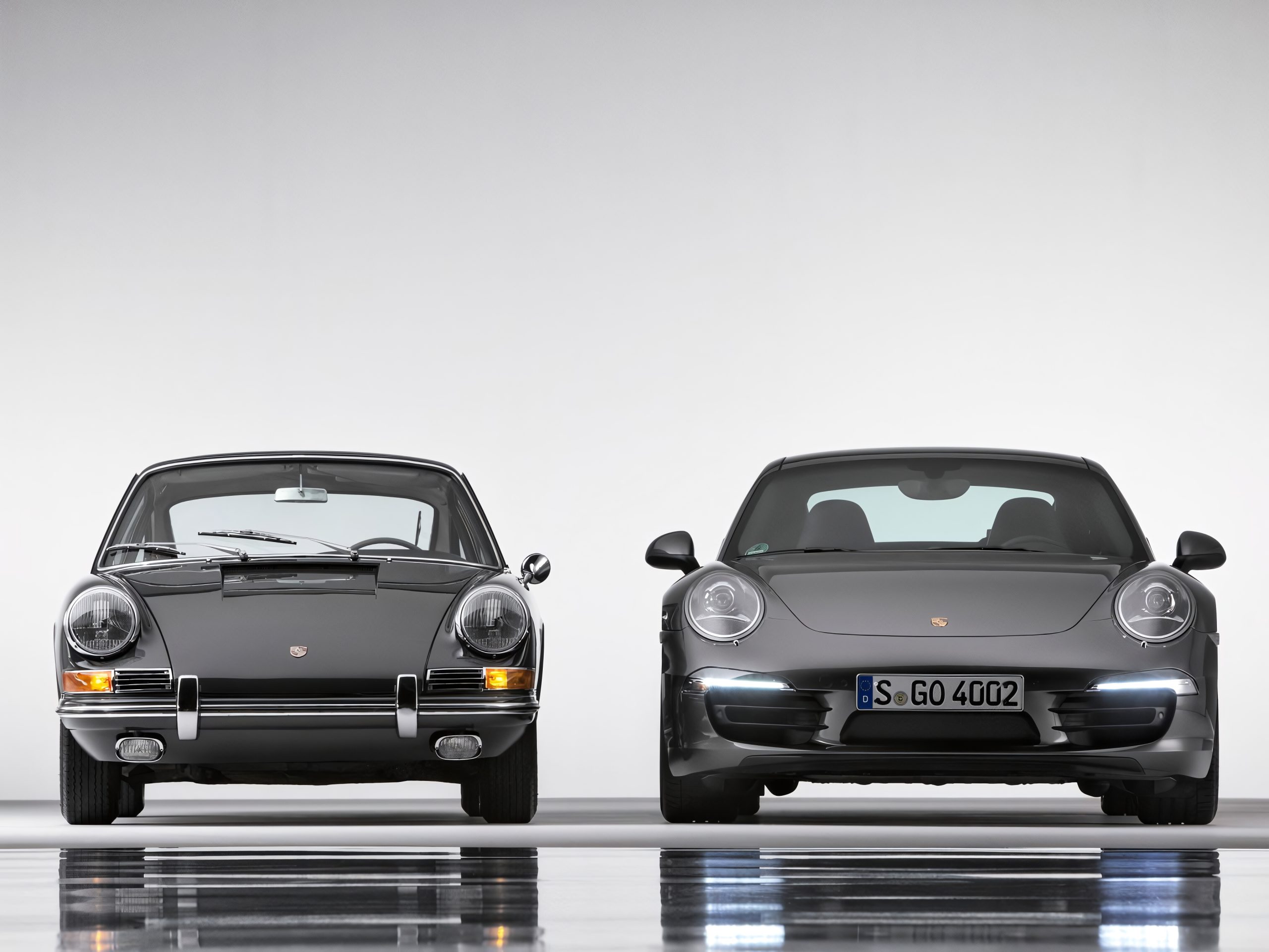 Modern gray Porsche 911 (991 generation) is displayed here alongside its classic ancestor