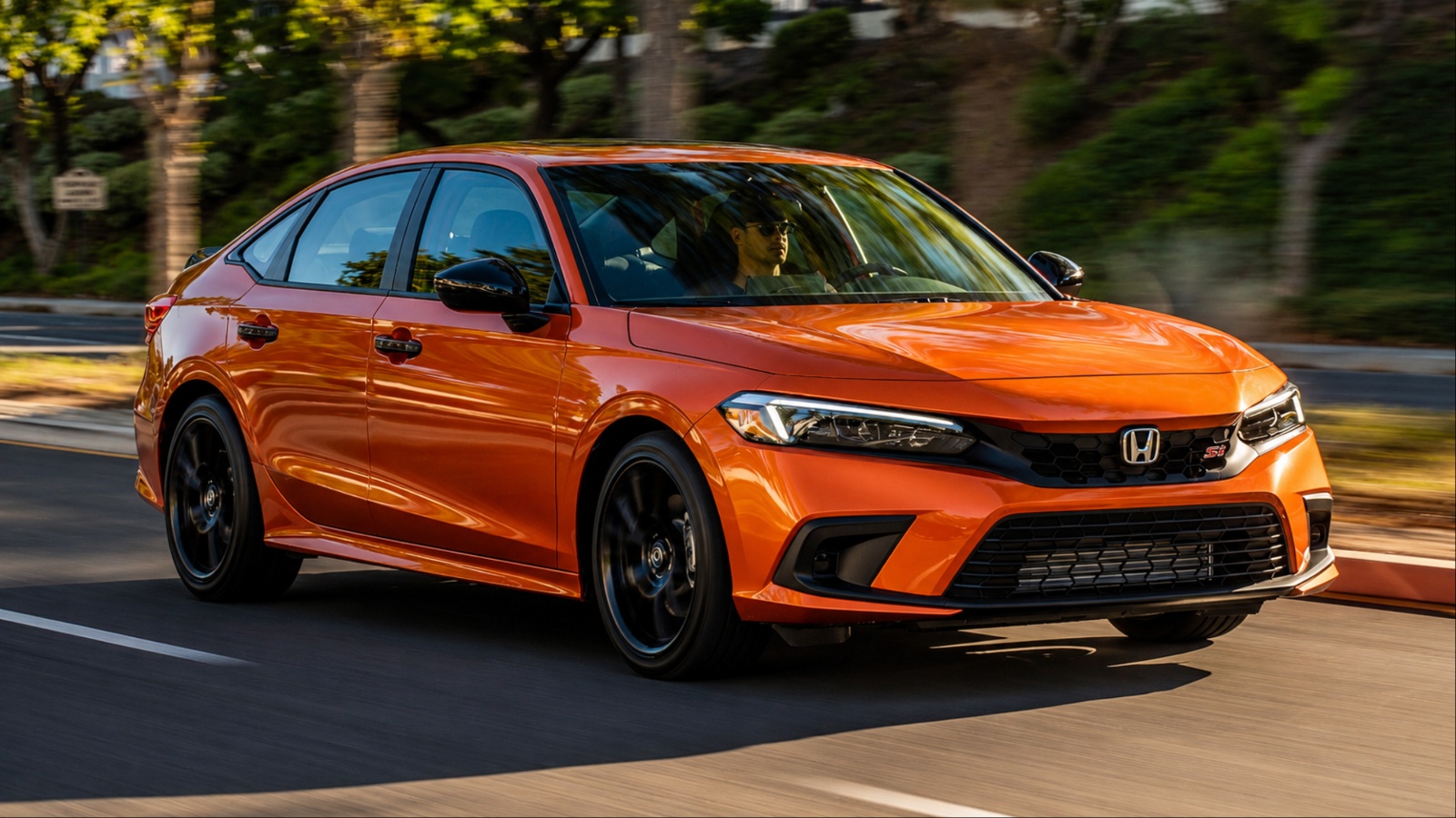 Honda Civic sedan driving through a tree-lined road in motion