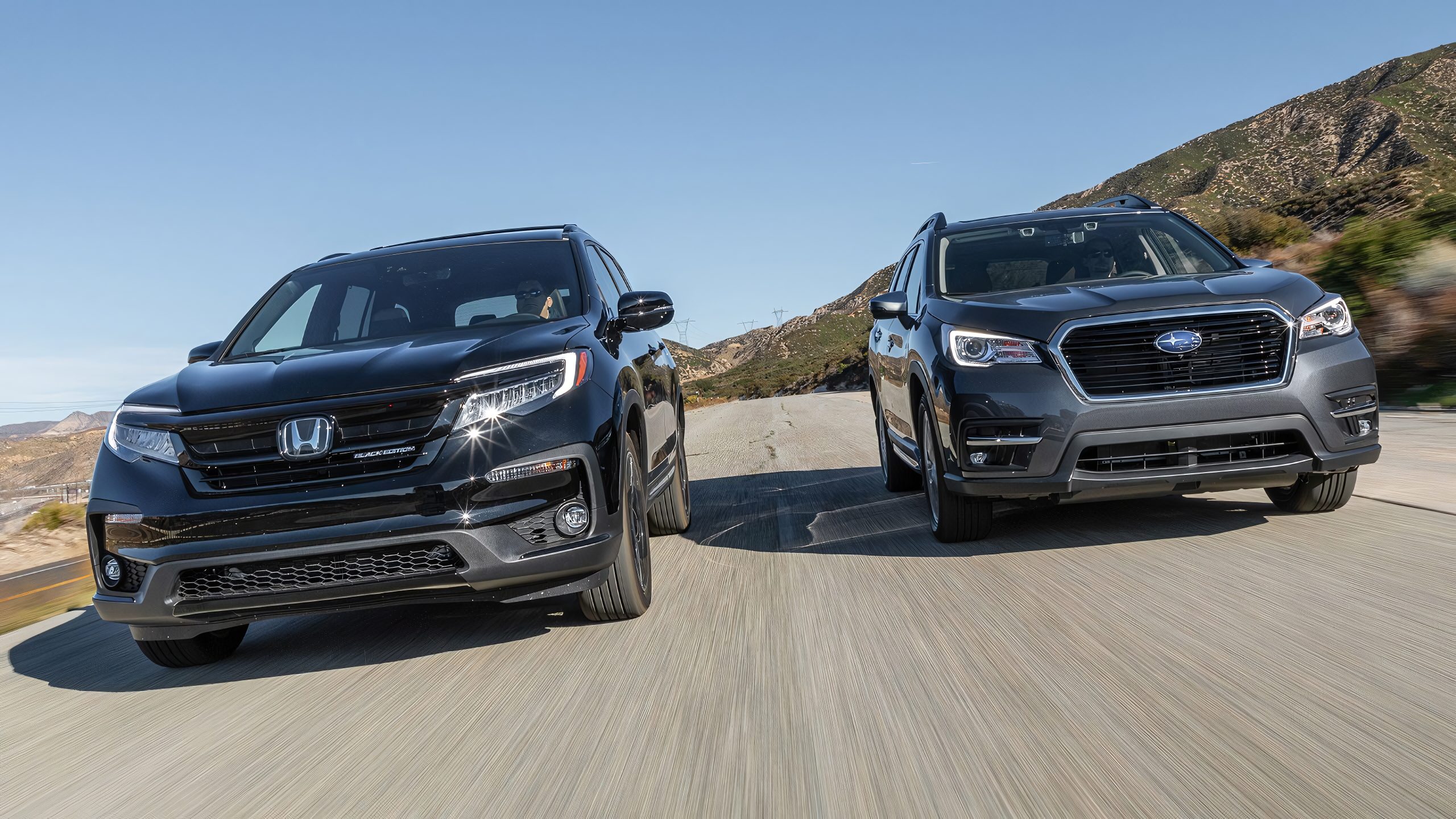 Honda Pilot and Subaru Ascent drive side-by-side on a scenic mountain road