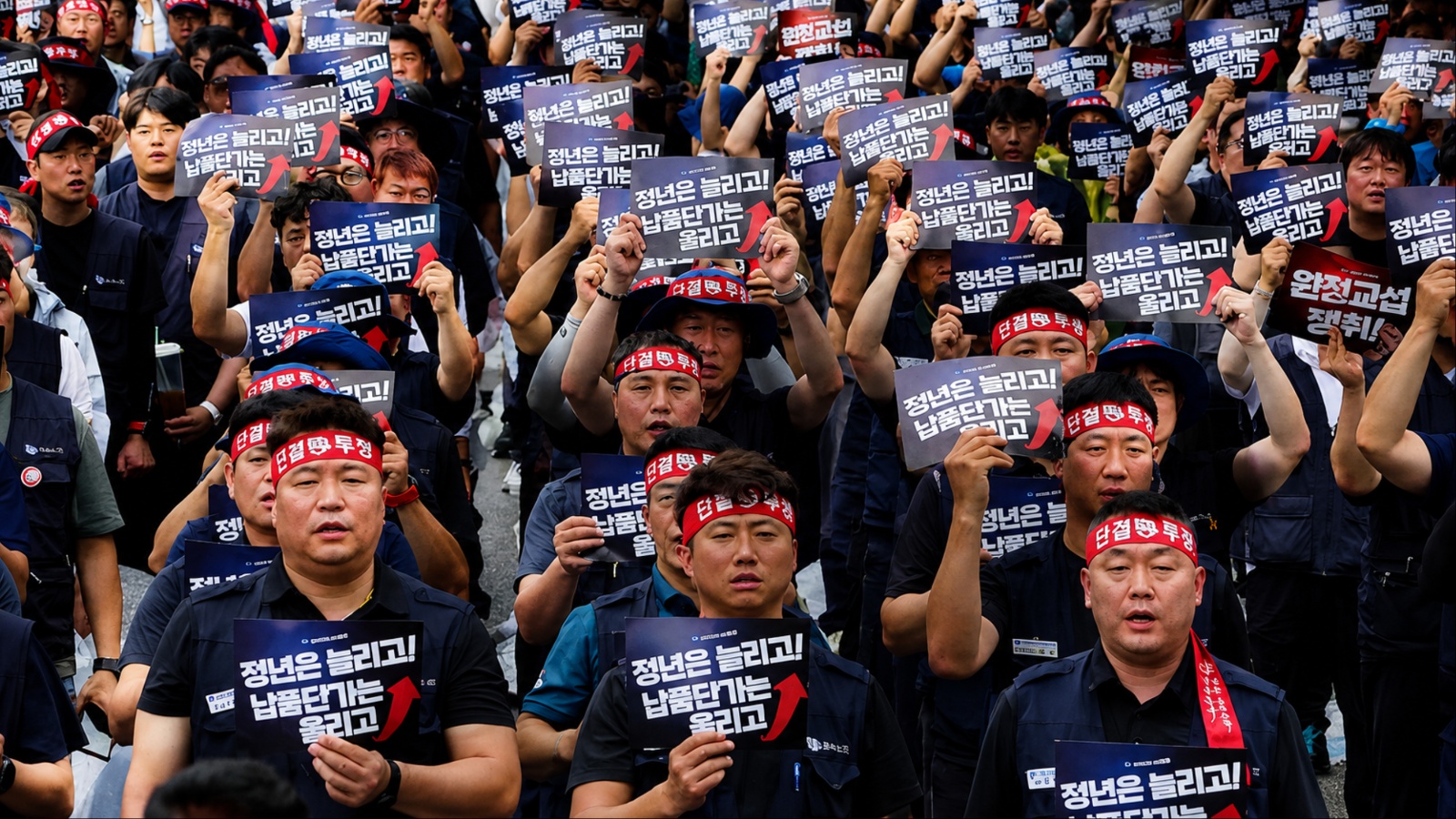 Hyundai workers gather during a rare strike, holding protest signs and raising fists