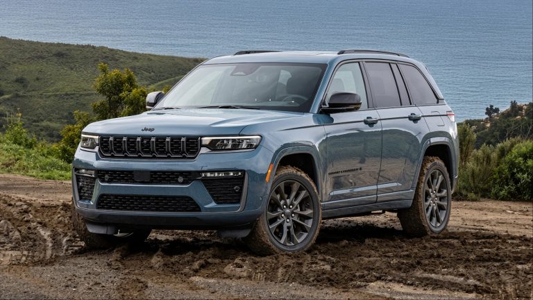 A Blue Jeep Grand Cherokee is standing on a muddy patch
