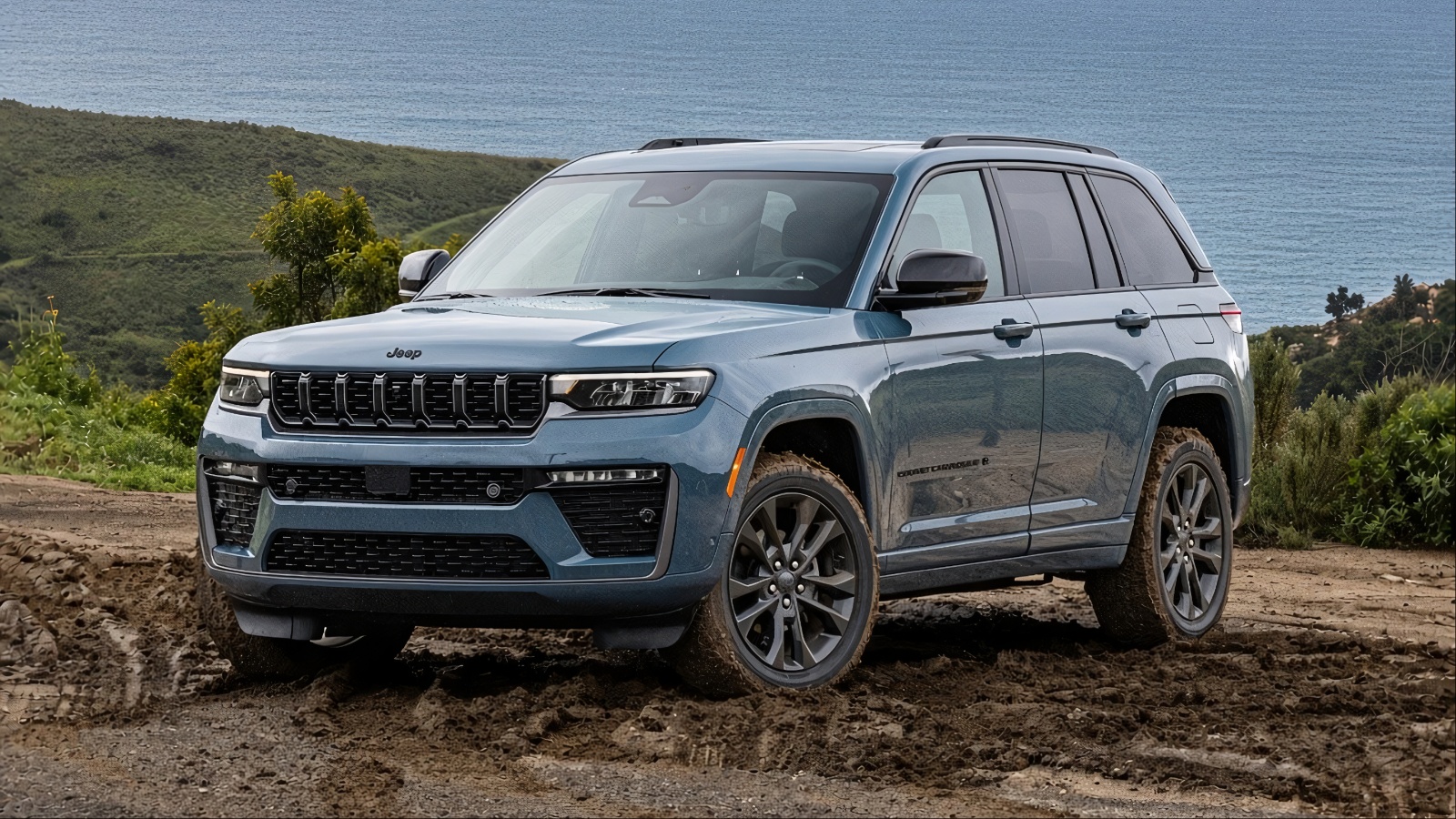 A Blue Jeep Grand Cherokee is standing on a muddy patch