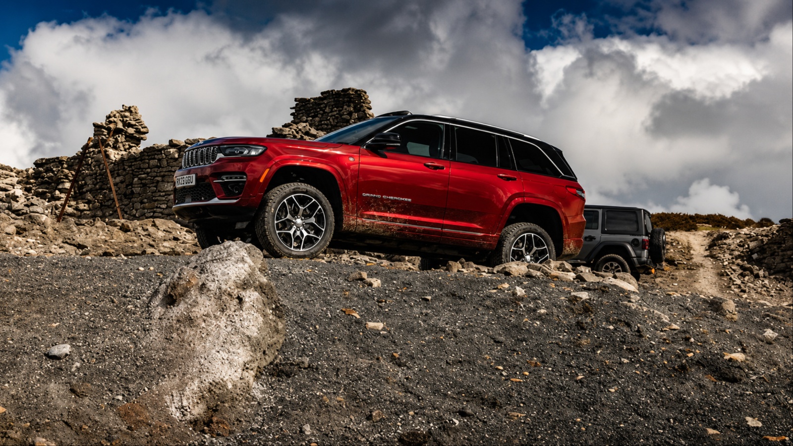 A red Jeep Grand Cherokee is standing on a hilly terrain