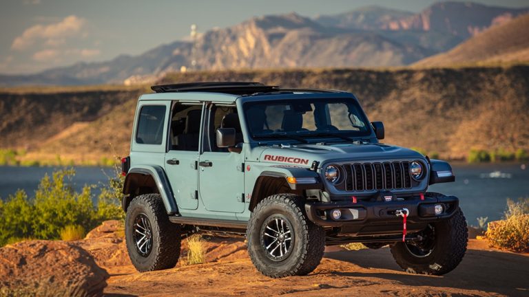 Jeep Wrangler Rubicon parked on rugged terrain with dramatic mountains and golden-hour lighting