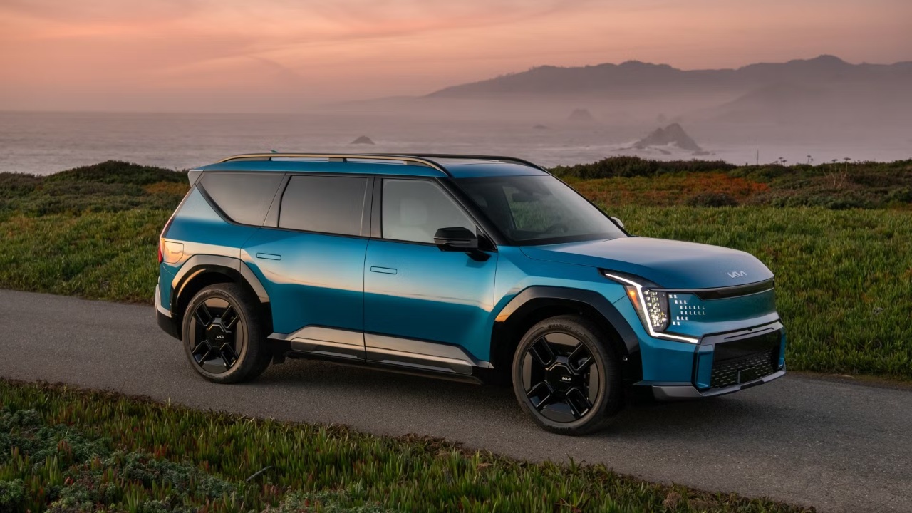 Kia EV9 parked along a coastal road overlooking the ocean at sunset