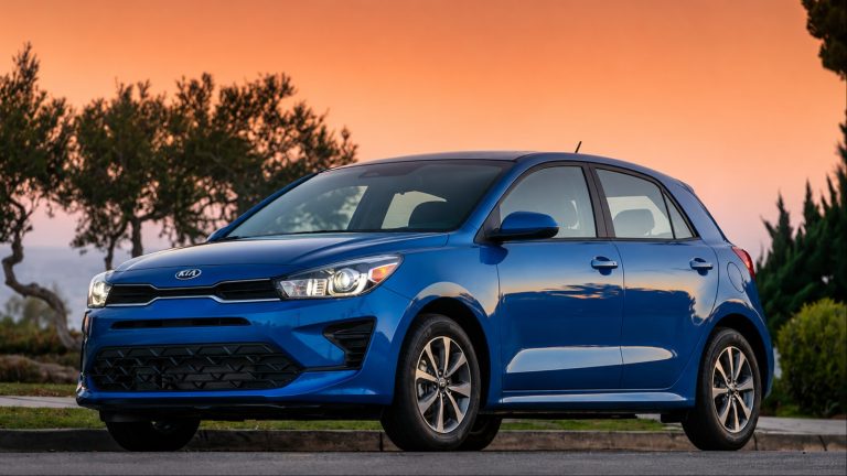 Kia Rio hatchback parked outdoors with trees and sunset in the background