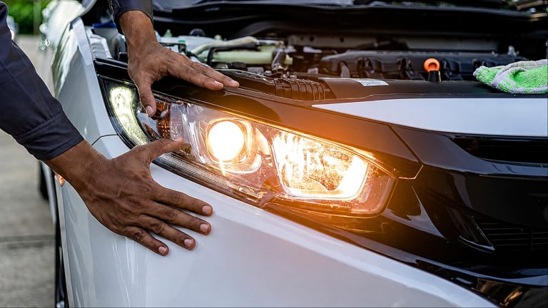 Mechanic inspecting a car headlight during routine vehicle maintenance and safety checks